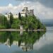 Niedzica Castle reflecting on the serene lake surrounded by lush greenery.